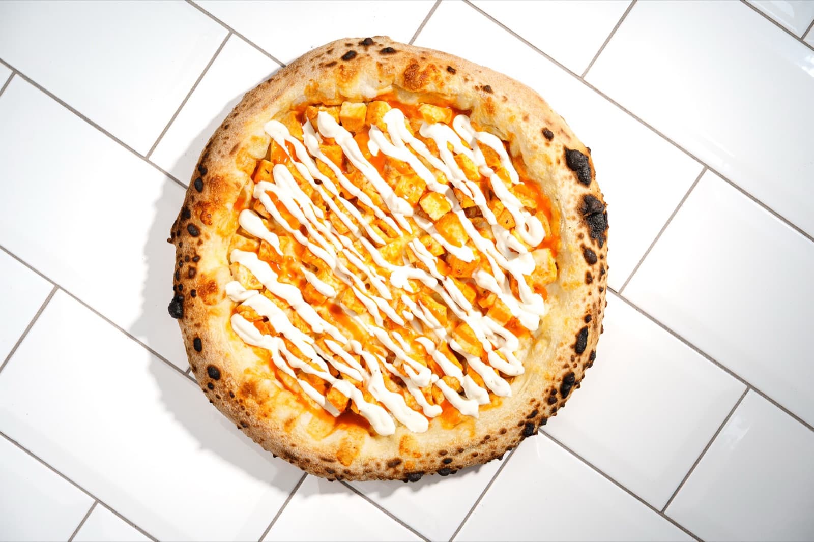 Pizza new-yorkaise ronde à la croûte gonflée, poulet buffalo et filets de sauce ranch