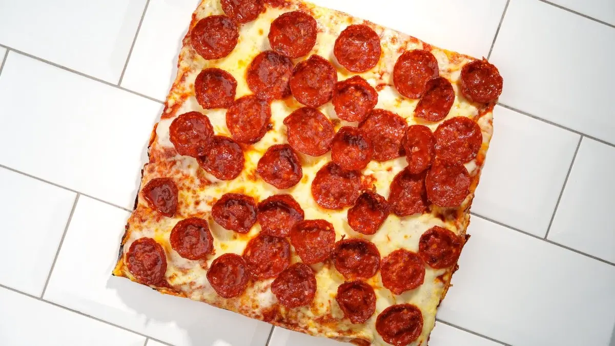 Pizza sicilienne carrée couverte de rondelles de pepperoni grillées sur mozzarella