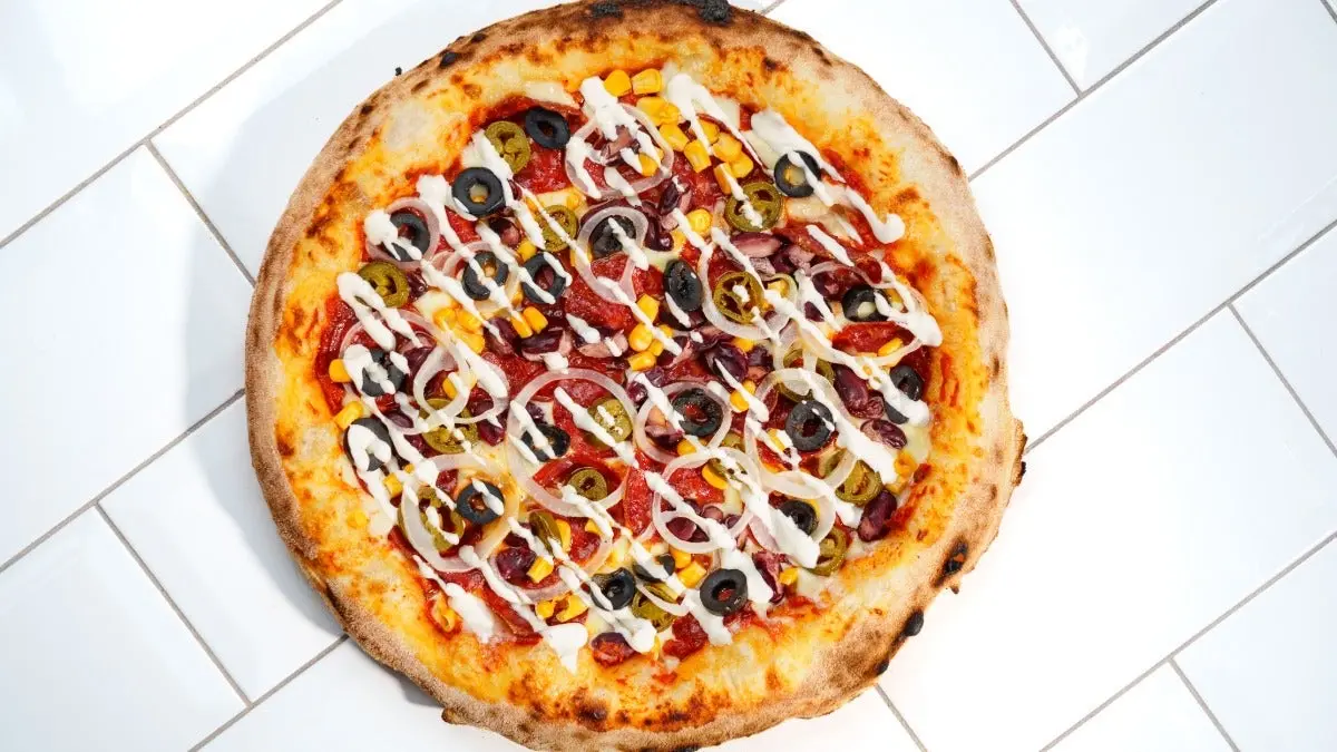 Pizza tex-mex garnie de poulet, légumes et sauce ranch